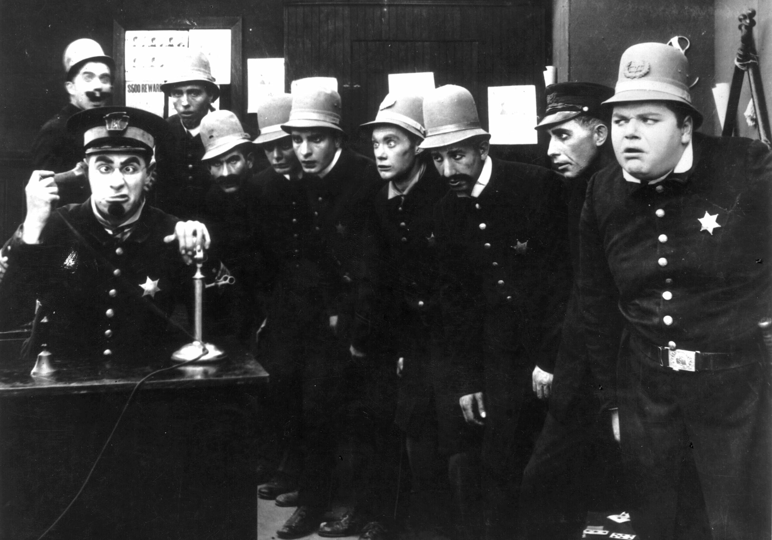 A scene from 'In the Clutches of the Gang', a Keystone Cops silent comedy directed by George Nichols and Mack Sennett. Left to right : Ford Sterling (on phone), Edgar Kennedy, George Jeskey, Al St John, Hank Mann, Rube Miller, and Roscoe Fatty Arbuckle (1887 - 1933).   (Photo by Hulton Archive/Getty Images)